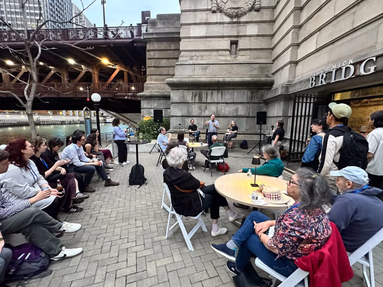 A crowd sits at tables listening to a panel of speakers at the McCormick Bridgehouse & Chicago River Museum.
